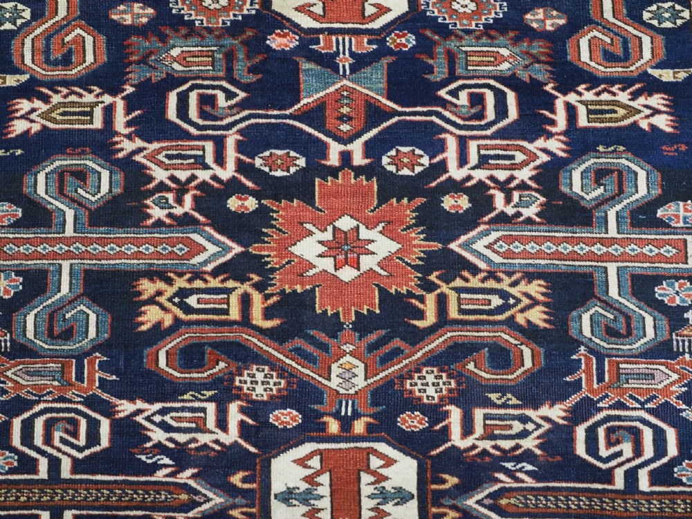 An antique hand-knotted Caucasian Perepedil rug featuring a navy blue field with geometric rams horn motifs and star medallions framed by multi-layered geometric borders. View IX