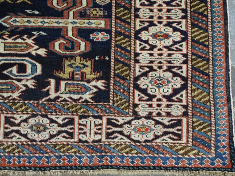 An antique hand-knotted Caucasian Perepedil rug featuring a navy blue field with geometric rams horn motifs and star medallions framed by multi-layered geometric borders. View XI