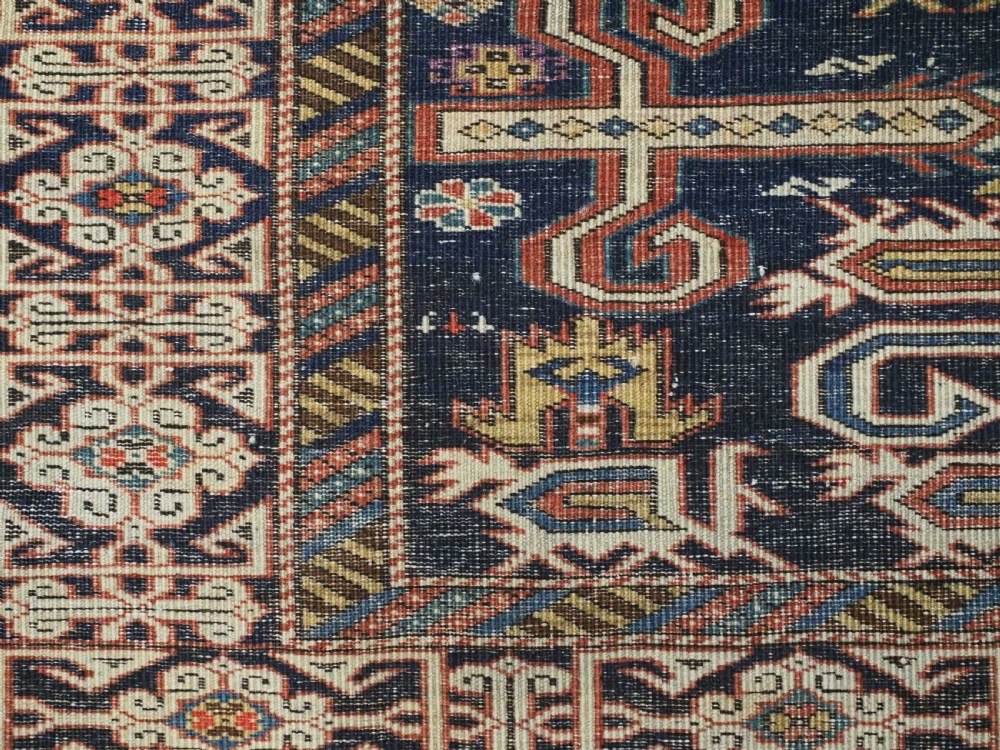 An antique hand-knotted Caucasian Perepedil rug featuring a navy blue field with geometric rams horn motifs and star medallions framed by multi-layered geometric borders. View XII