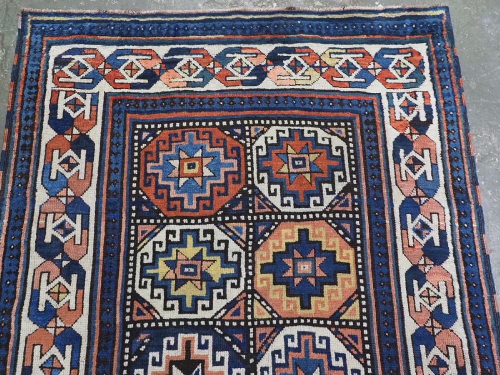 An antique Caucasian Moghan Kazak hand-knotted wool runner rug featuring a repeating geometric Memling gul pattern in navy, terracotta, ochre, and cream. View III