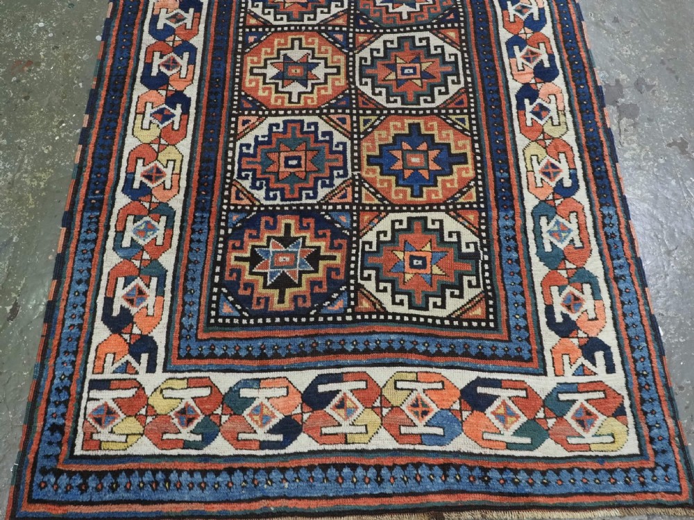 An antique Caucasian Moghan Kazak hand-knotted wool runner rug featuring a repeating geometric Memling gul pattern in navy, terracotta, ochre, and cream. View VI