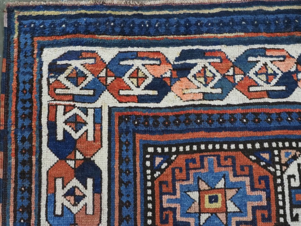An antique Caucasian Moghan Kazak hand-knotted wool runner rug featuring a repeating geometric Memling gul pattern in navy, terracotta, ochre, and cream. View VII