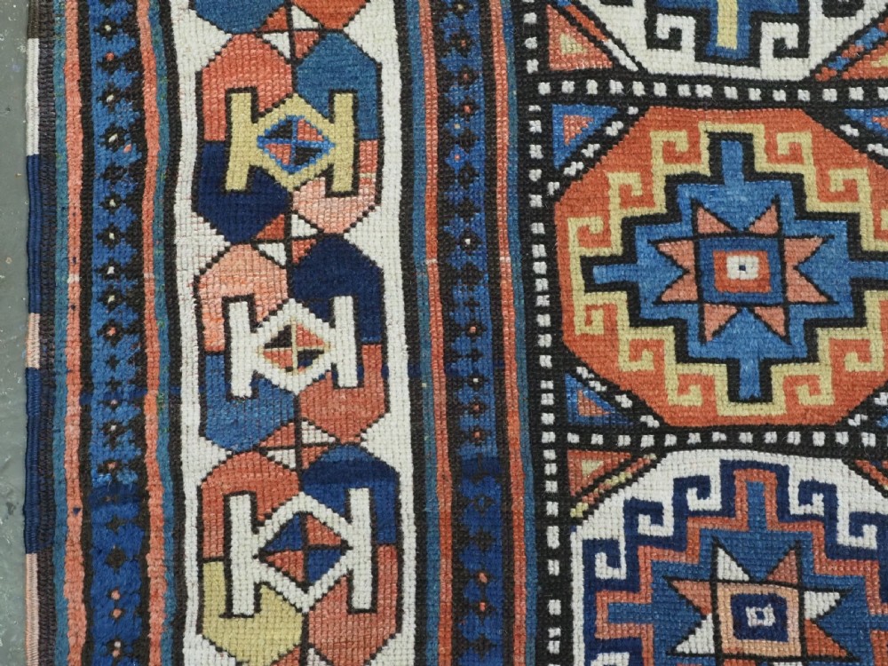 An antique Caucasian Moghan Kazak hand-knotted wool runner rug featuring a repeating geometric Memling gul pattern in navy, terracotta, ochre, and cream. View VIII