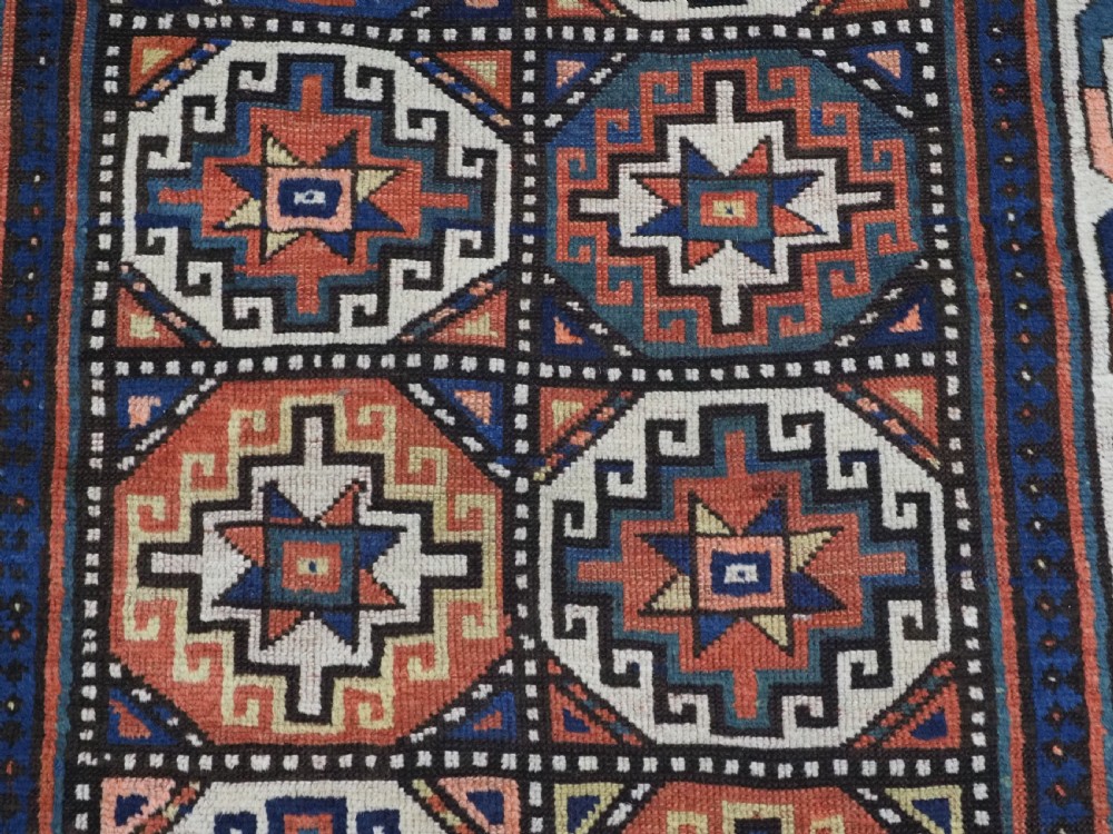 An antique Caucasian Moghan Kazak hand-knotted wool runner rug featuring a repeating geometric Memling gul pattern in navy, terracotta, ochre, and cream. View XI