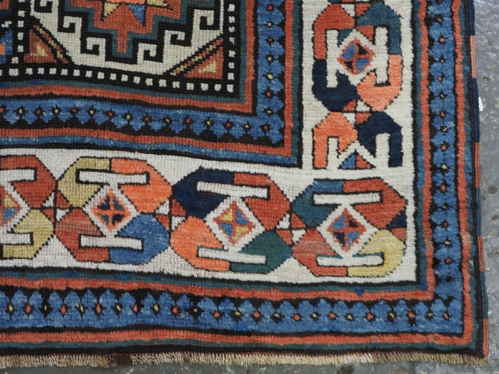 An antique Caucasian Moghan Kazak hand-knotted wool runner rug featuring a repeating geometric Memling gul pattern in navy, terracotta, ochre, and cream. View XII