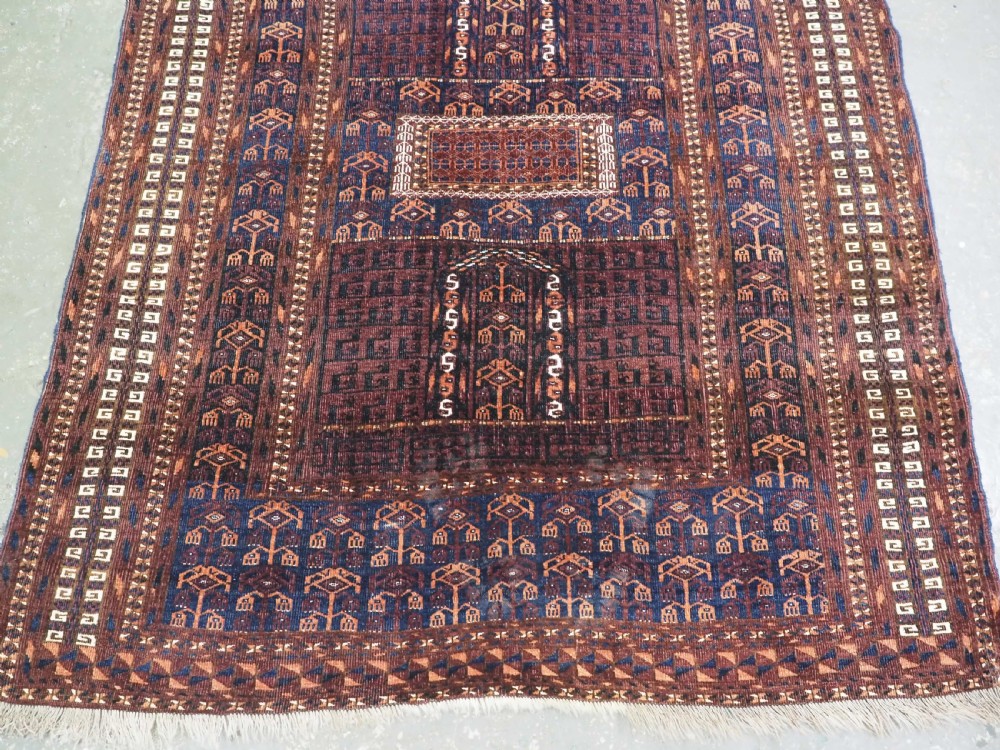An antique 19th-century Saryk Turkmen ensi rug with a dark reddish-brown field featuring geometric cross divisions and white cotton highlights. View V