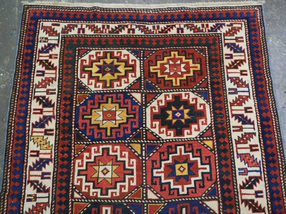 An antique Caucasian Moghan Kazak hand-knotted wool rug featuring two vertical columns of geometric Memling guls inside a multi-tiered border. View III