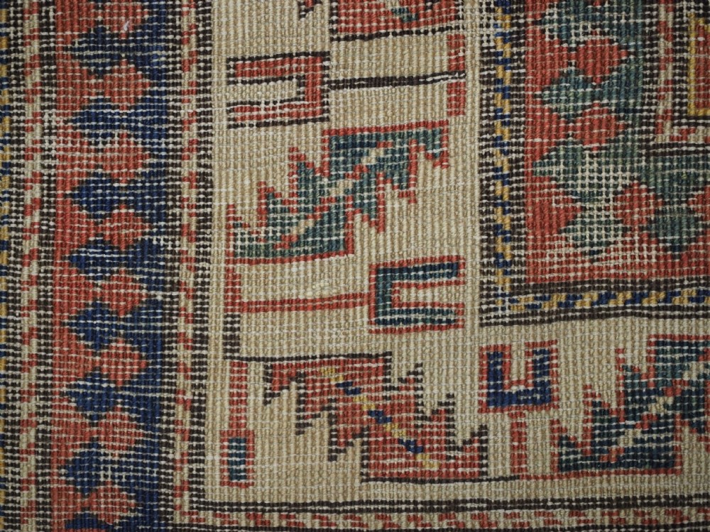 An antique Caucasian Moghan Kazak hand-knotted wool rug featuring two vertical columns of geometric Memling guls inside a multi-tiered border. View XI