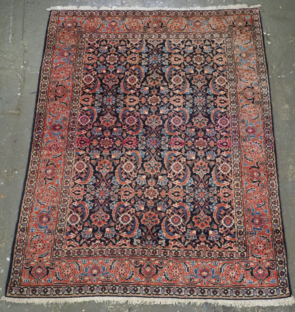An antique hand-knotted wool Tabriz rug featuring a dense repeating Herati design in navy blue, terracotta, and beige with a multi-band decorative border.