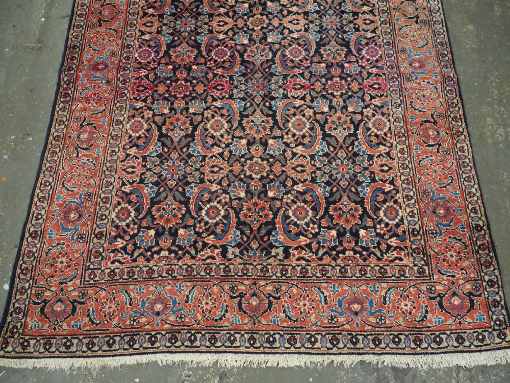 An antique hand-knotted wool Tabriz rug featuring a dense repeating Herati design in navy blue, terracotta, and beige with a multi-band decorative border. View V