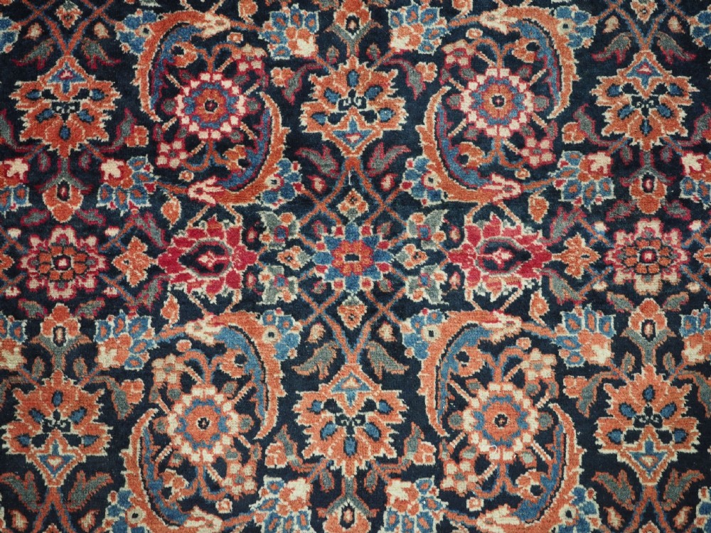 An antique hand-knotted wool Tabriz rug featuring a dense repeating Herati design in navy blue, terracotta, and beige with a multi-band decorative border. View IX