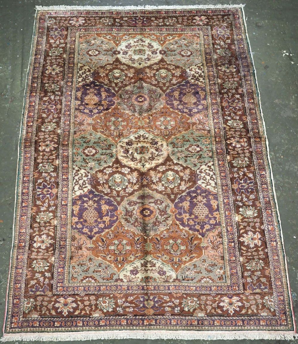 A rectangular vintage Turkish Kayseri rug featuring intricate floral lattice motifs and medallions in shades of brown, terracotta, purple, and green with a decorative bordered edge and fringed ends.