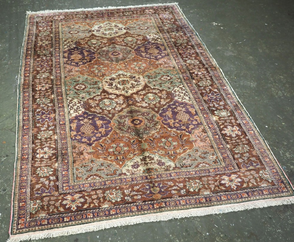 A rectangular vintage Turkish Kayseri rug featuring intricate floral lattice motifs and medallions in shades of brown, terracotta, purple, and green with a decorative bordered edge and fringed ends. View II