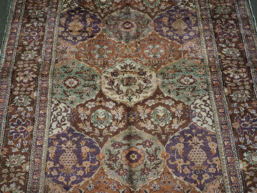 A rectangular vintage Turkish Kayseri rug featuring intricate floral lattice motifs and medallions in shades of brown, terracotta, purple, and green with a decorative bordered edge and fringed ends. View IV