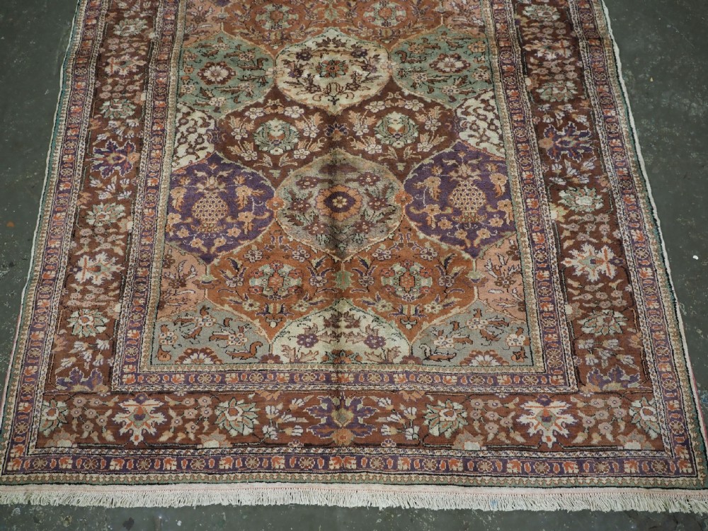 A rectangular vintage Turkish Kayseri rug featuring intricate floral lattice motifs and medallions in shades of brown, terracotta, purple, and green with a decorative bordered edge and fringed ends. View V