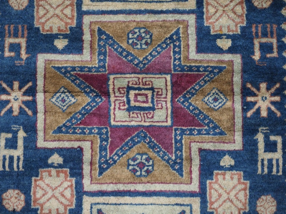 An antique Caucasian hand-knotted wool rug featuring three star medallions on a navy blue field with geometric borders. View IX