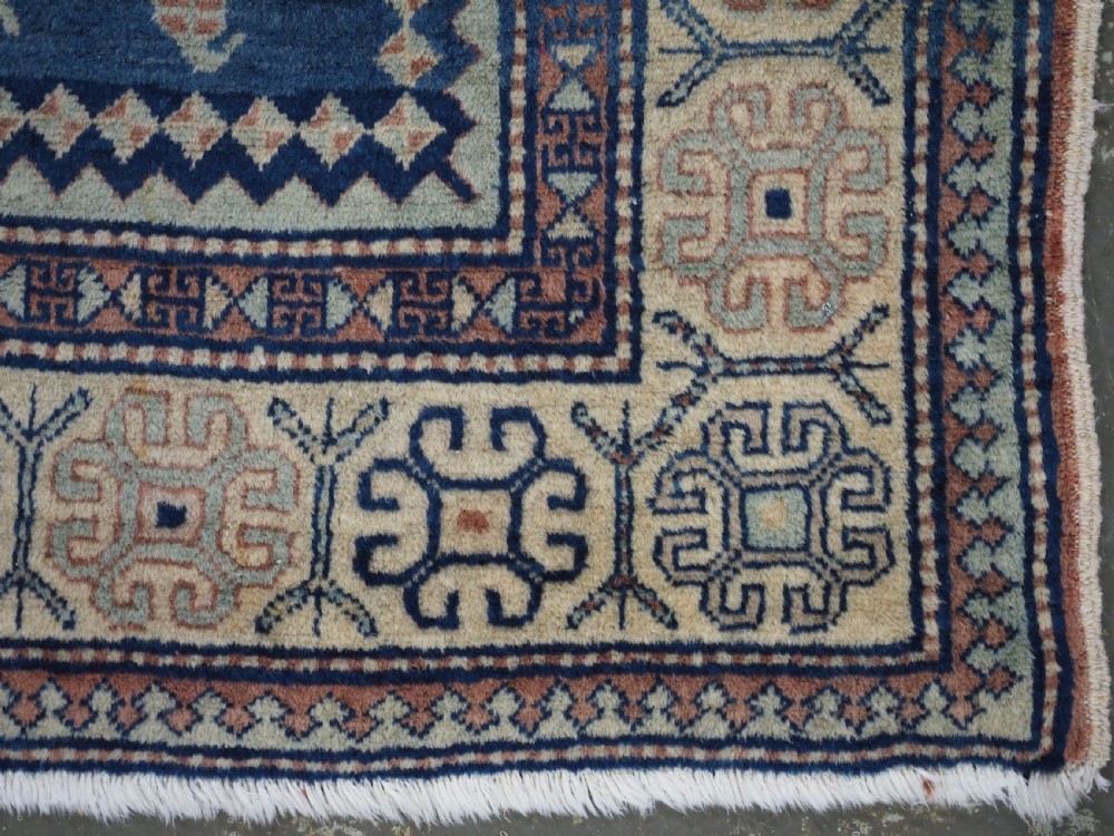 An antique Caucasian hand-knotted wool rug featuring three star medallions on a navy blue field with geometric borders. View XI