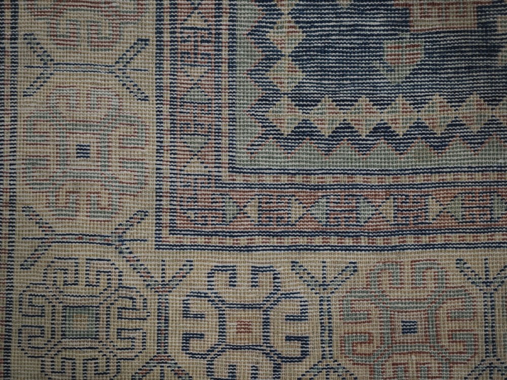 An antique Caucasian hand-knotted wool rug featuring three star medallions on a navy blue field with geometric borders. View XII