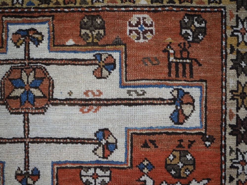 An antique hand-knotted Caucasian Shirvan wool rug with geometric central medallions, zoomorphic figures, and tribal borders in terracotta, cream, and navy blue. View VII
