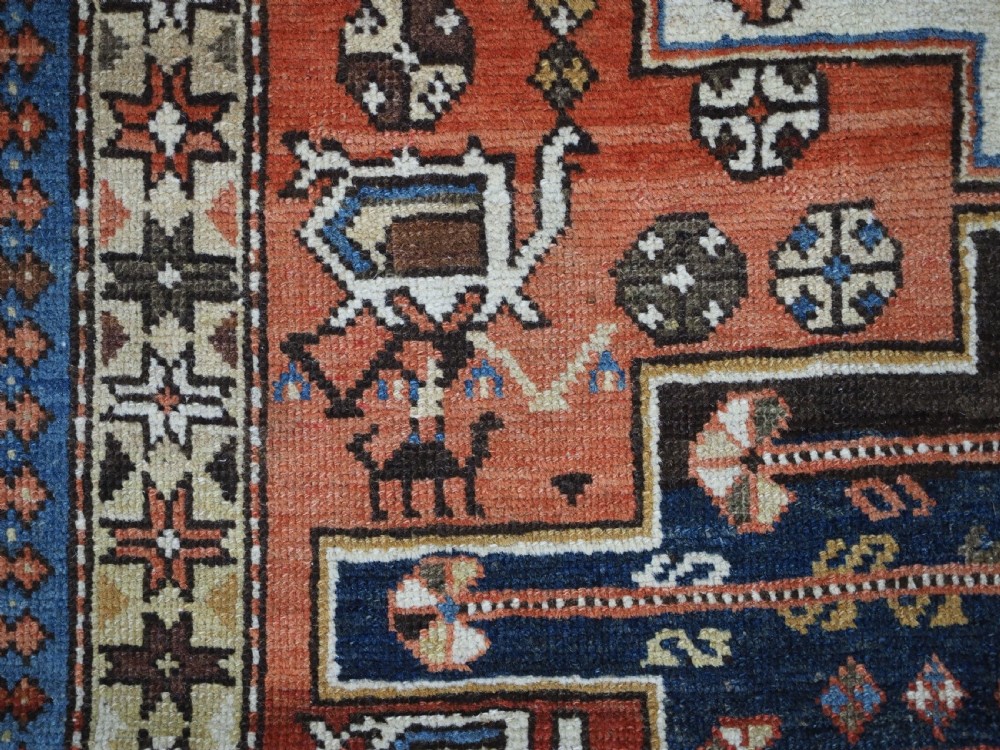 An antique hand-knotted Caucasian Shirvan wool rug with geometric central medallions, zoomorphic figures, and tribal borders in terracotta, cream, and navy blue. View VIII