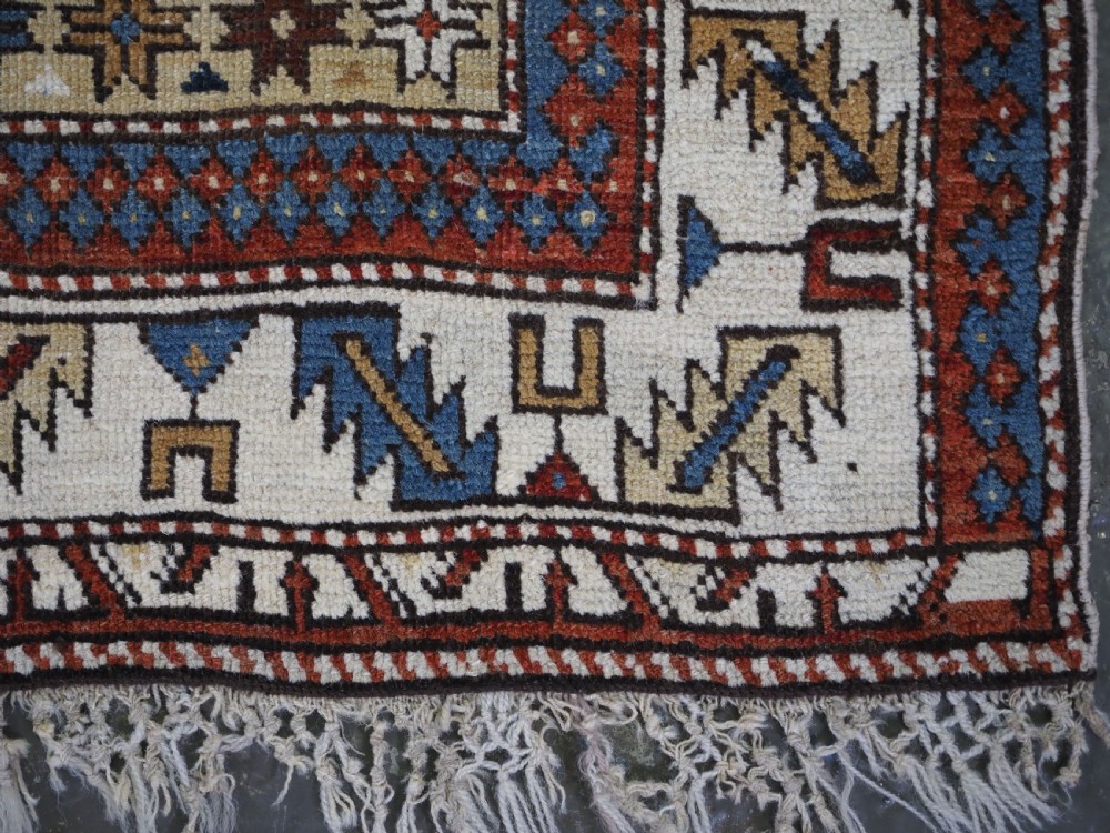 An antique hand-knotted Caucasian Shirvan wool rug with geometric central medallions, zoomorphic figures, and tribal borders in terracotta, cream, and navy blue. View XIII