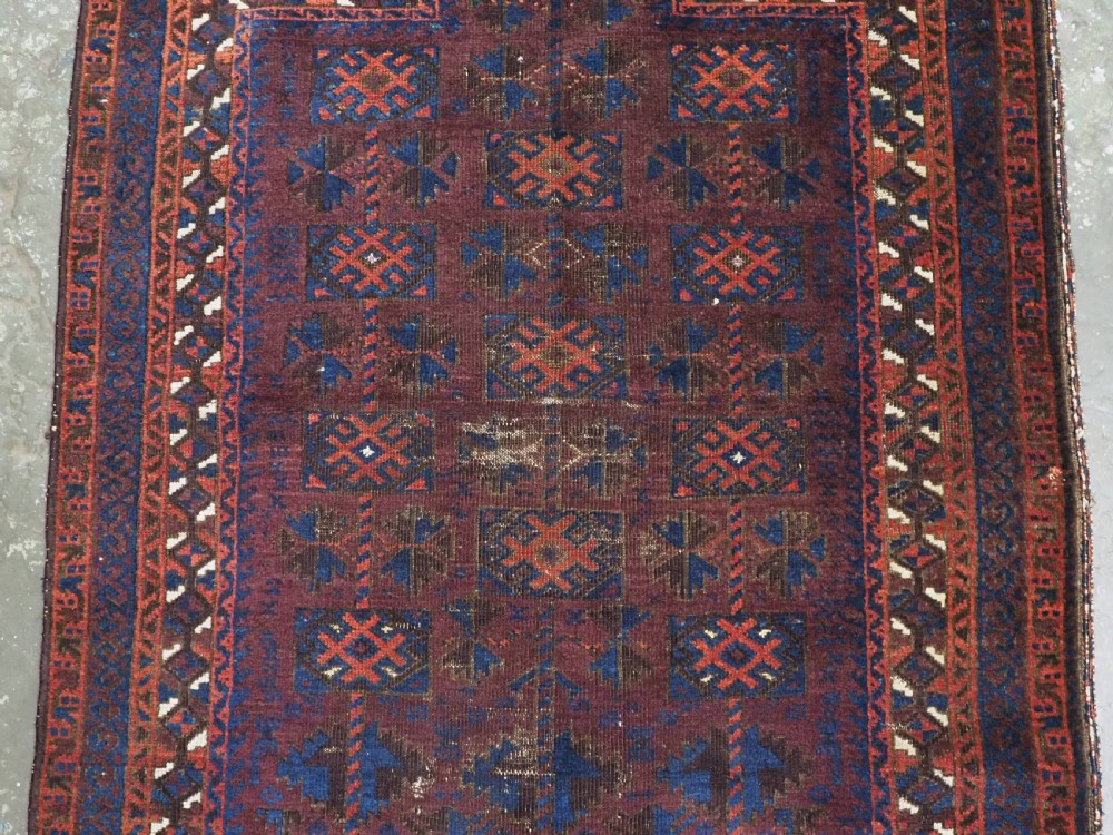An antique hand-knotted wool prayer rug featuring a defined mihrab arch, geometric box patterns, and deep aubergine, rust red, and indigo blue tones. View IV