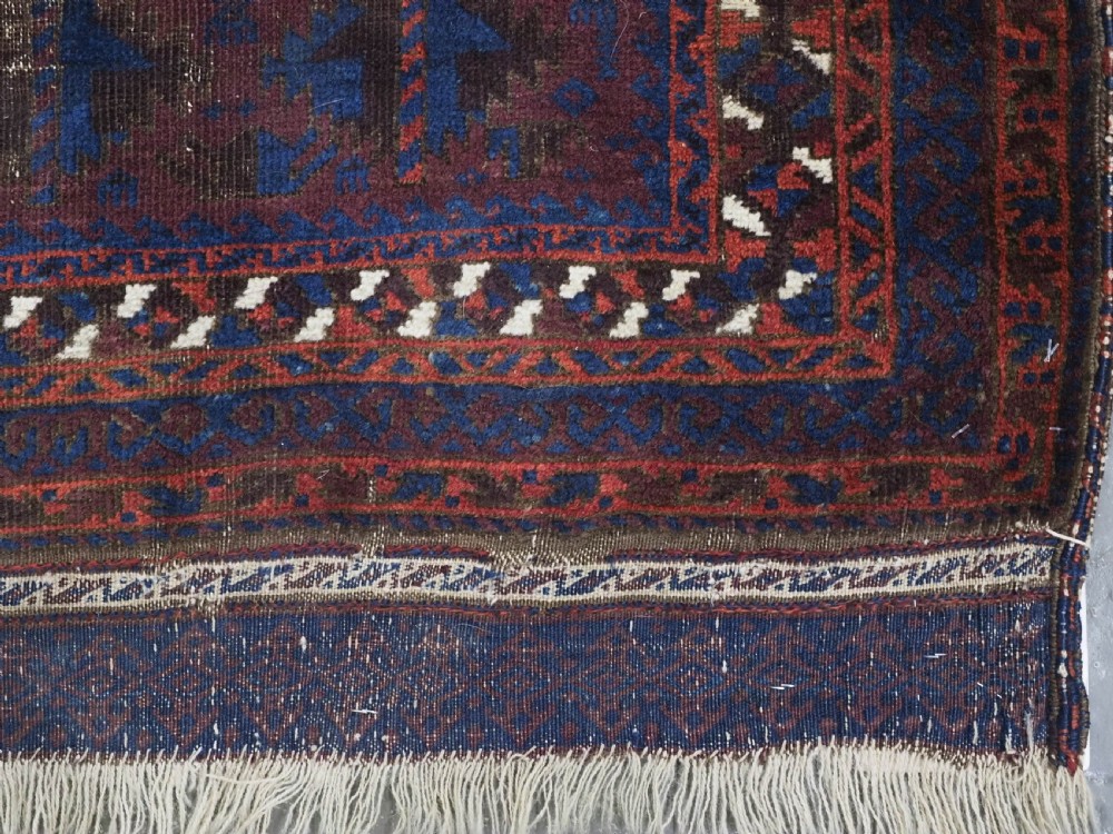 An antique hand-knotted wool prayer rug featuring a defined mihrab arch, geometric box patterns, and deep aubergine, rust red, and indigo blue tones. View X