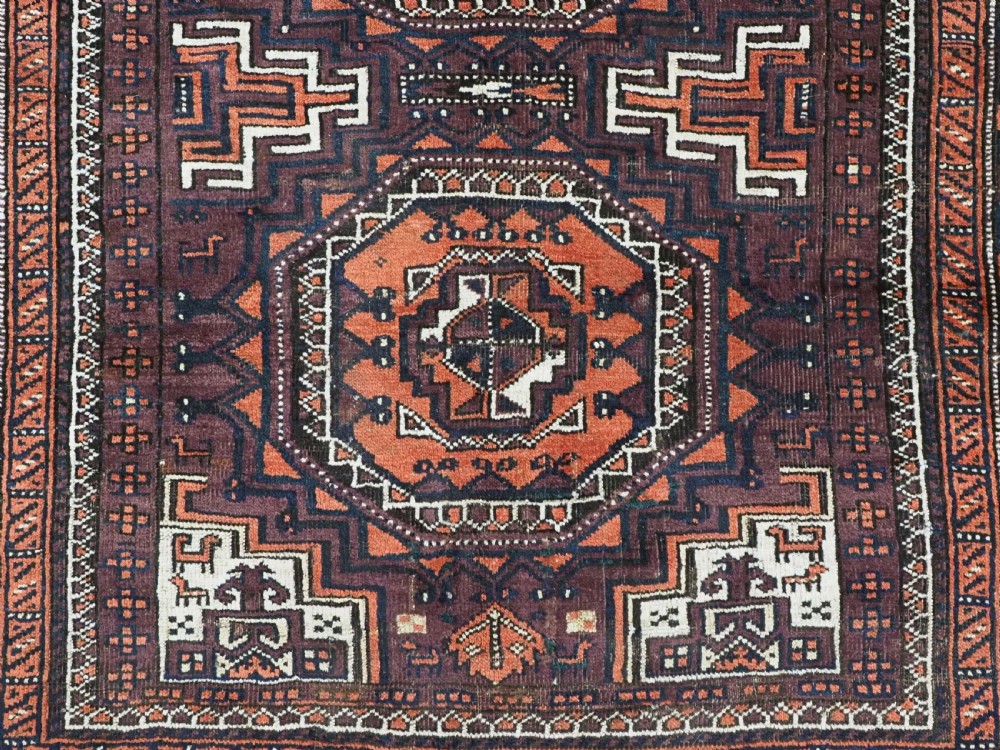 An antique hand-knotted wool Baluch rug featuring four octagonal central medallions on a deep aubergine ground with geometric borders. View XI