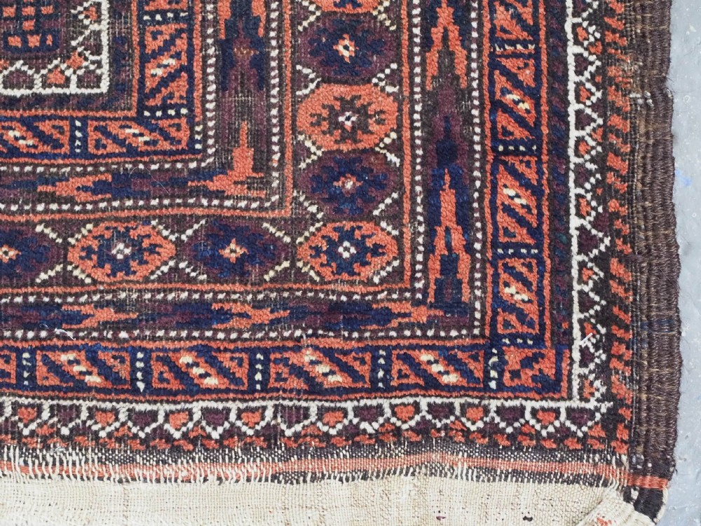 An antique hand-knotted wool Baluch rug featuring four octagonal central medallions on a deep aubergine ground with geometric borders. View XIII