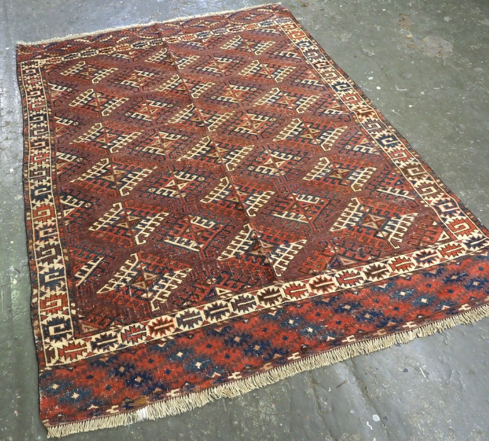 A hand-knotted antique Yomut Turkmen wool rug featuring repeating diamond-shaped geometric guls in red, navy, brown, and cream with patterned borders. View II
