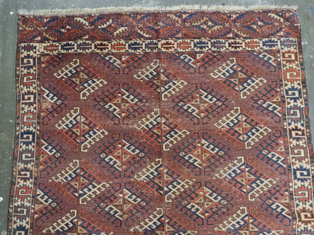 A hand-knotted antique Yomut Turkmen wool rug featuring repeating diamond-shaped geometric guls in red, navy, brown, and cream with patterned borders. View III