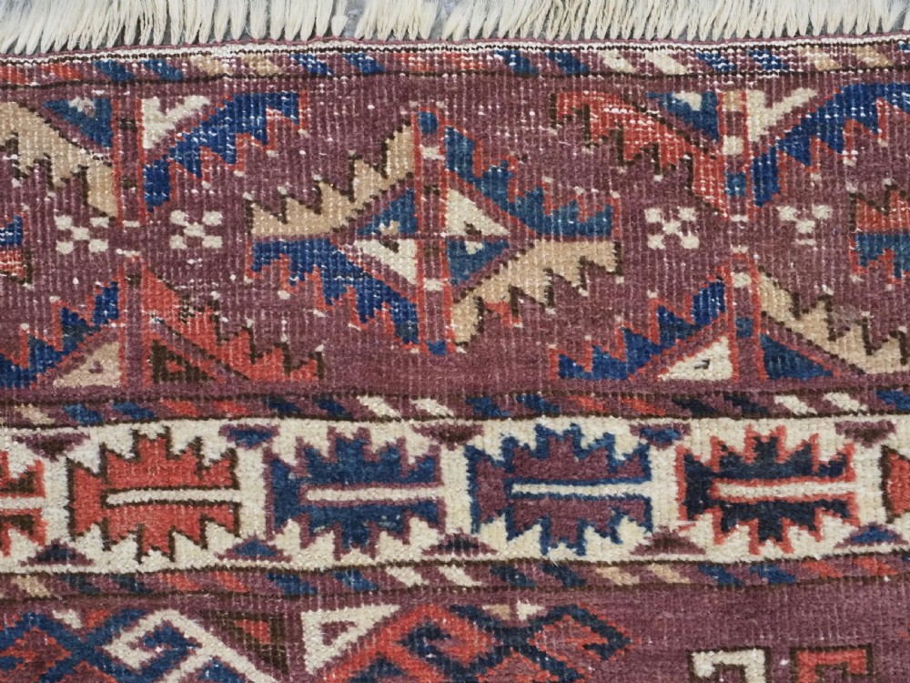 A hand-knotted antique Yomut Turkmen wool rug featuring repeating diamond-shaped geometric guls in red, navy, brown, and cream with patterned borders. View VIII