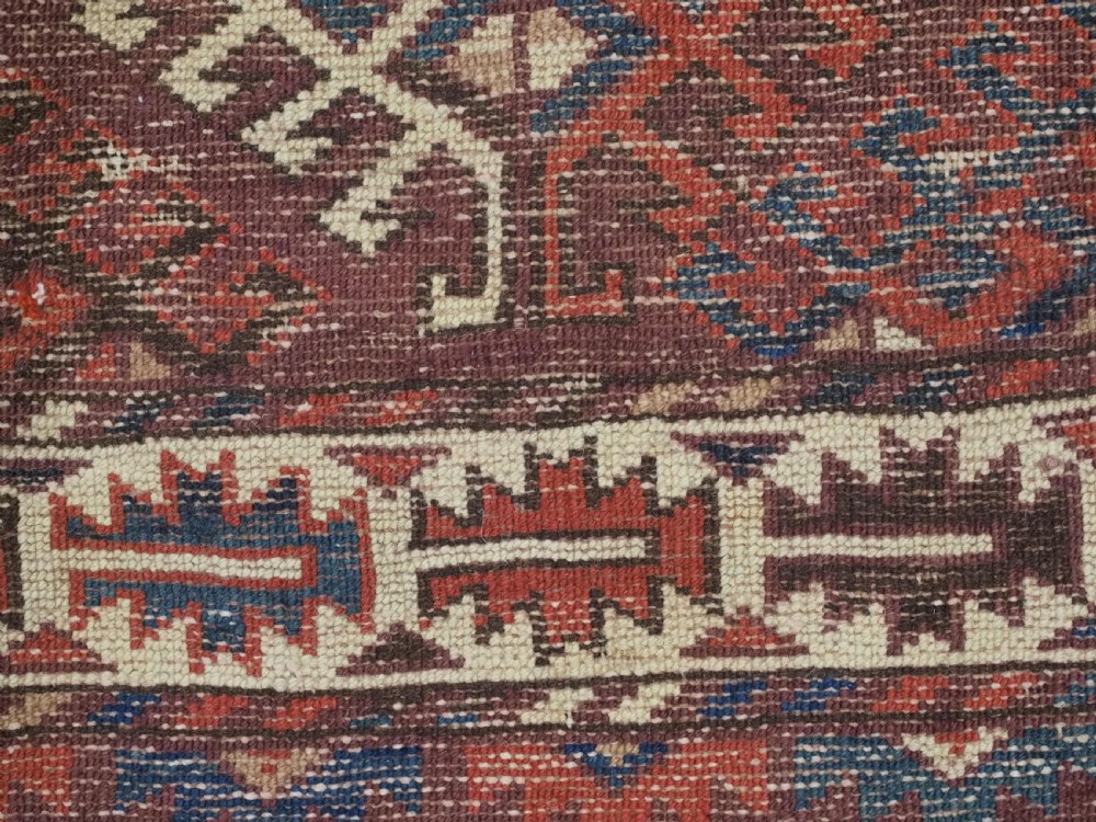 A hand-knotted antique Yomut Turkmen wool rug featuring repeating diamond-shaped geometric guls in red, navy, brown, and cream with patterned borders. View XIII