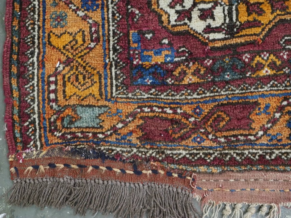 An antique hand-knotted Quchan Kurd rug featuring repeating cream and mustard octagonal Turkmen gul motifs set against a deep red field with geometric borders. View XI