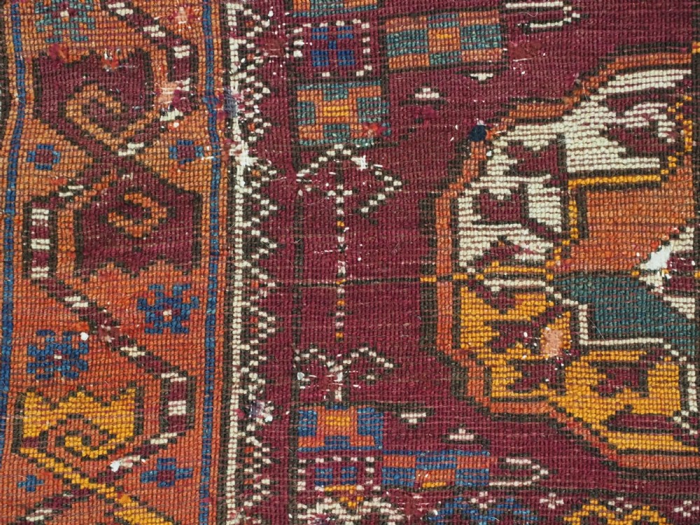 An antique hand-knotted Quchan Kurd rug featuring repeating cream and mustard octagonal Turkmen gul motifs set against a deep red field with geometric borders. View XII