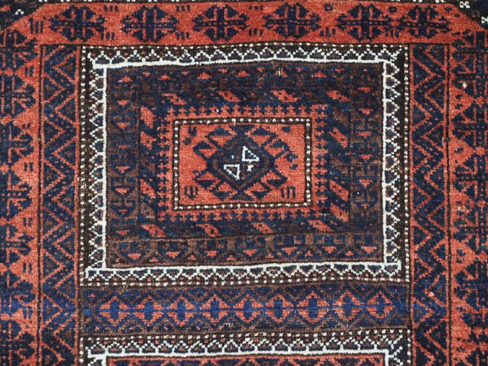 An antique Baluch hand-knotted wool rug featuring five geometric square medallions along a central field in deep red, dark navy blue, and terracotta tones. View VIII