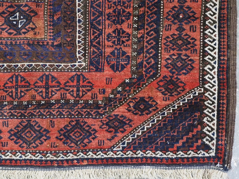 An antique Baluch hand-knotted wool rug featuring five geometric square medallions along a central field in deep red, dark navy blue, and terracotta tones. View XI