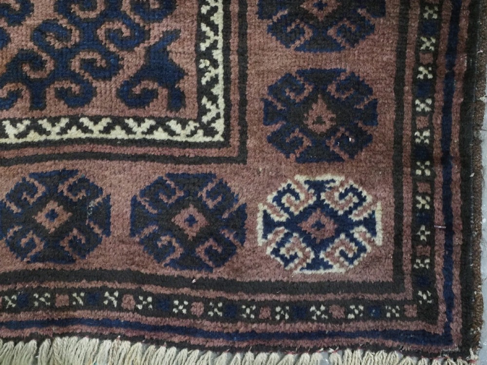 An antique hand-knotted Afghan Baluch wool rug featuring repeating geometric diamond motifs in dark brown and indigo blue tones. View XI