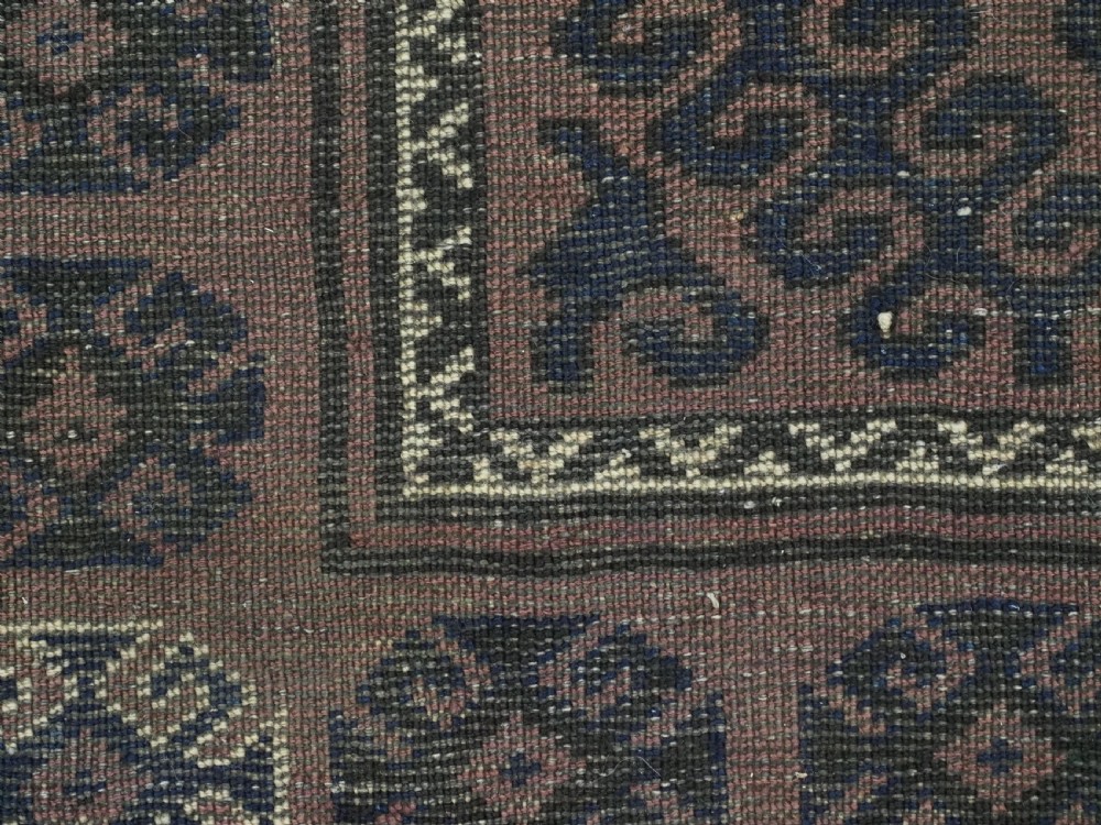 An antique hand-knotted Afghan Baluch wool rug featuring repeating geometric diamond motifs in dark brown and indigo blue tones. View XII