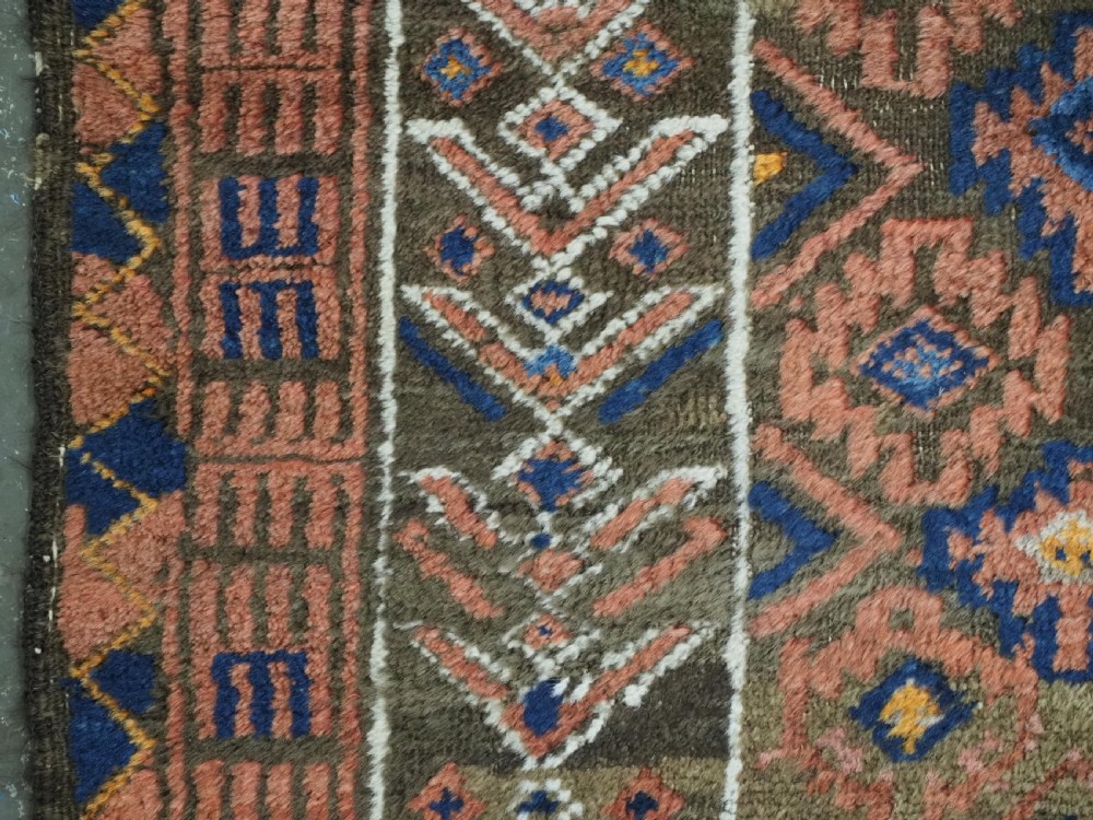 An antique hand-knotted wool prayer rug featuring a three-niche architectural design in terracotta, dark brown, and indigo blue tones with fringed edges. View VII