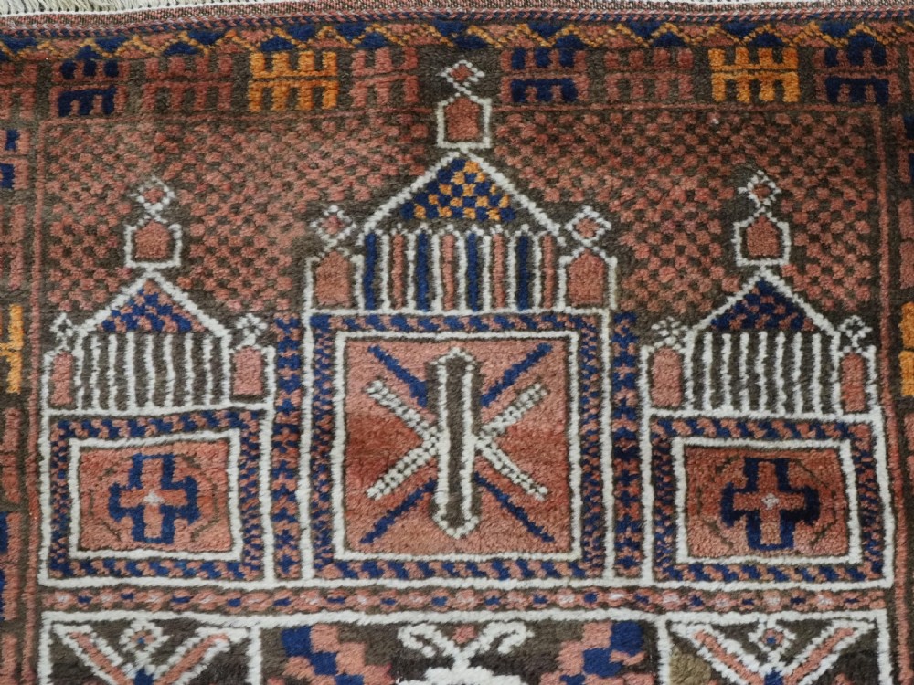 An antique hand-knotted wool prayer rug featuring a three-niche architectural design in terracotta, dark brown, and indigo blue tones with fringed edges. View VIII