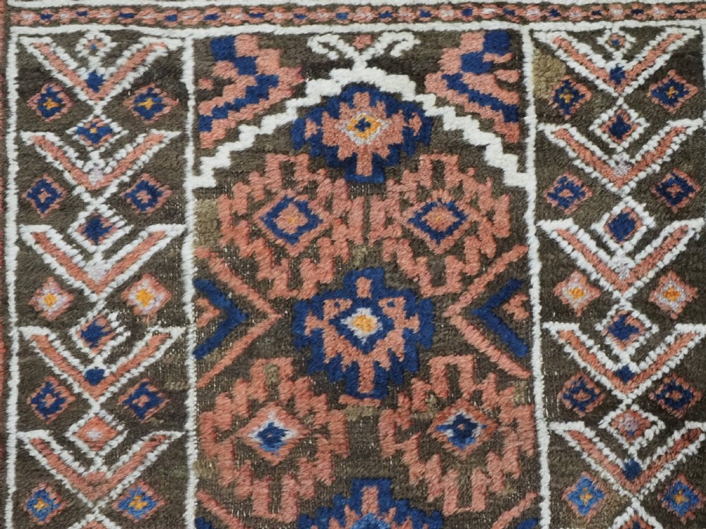 An antique hand-knotted wool prayer rug featuring a three-niche architectural design in terracotta, dark brown, and indigo blue tones with fringed edges. View IX