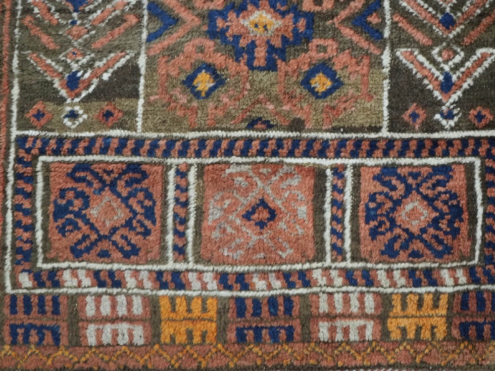 An antique hand-knotted wool prayer rug featuring a three-niche architectural design in terracotta, dark brown, and indigo blue tones with fringed edges. View XI
