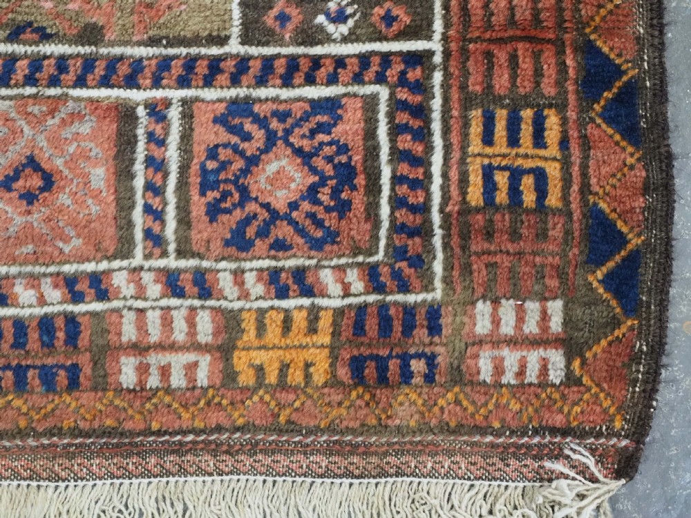 An antique hand-knotted wool prayer rug featuring a three-niche architectural design in terracotta, dark brown, and indigo blue tones with fringed edges. View XII
