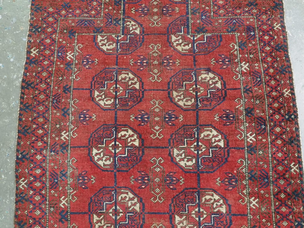 A hand-knotted antique Baluch prayer rug featuring a deep red ground, geometric octagonal medallions, an arched mihrab motif at the top, and multi-band patterned borders. View IV