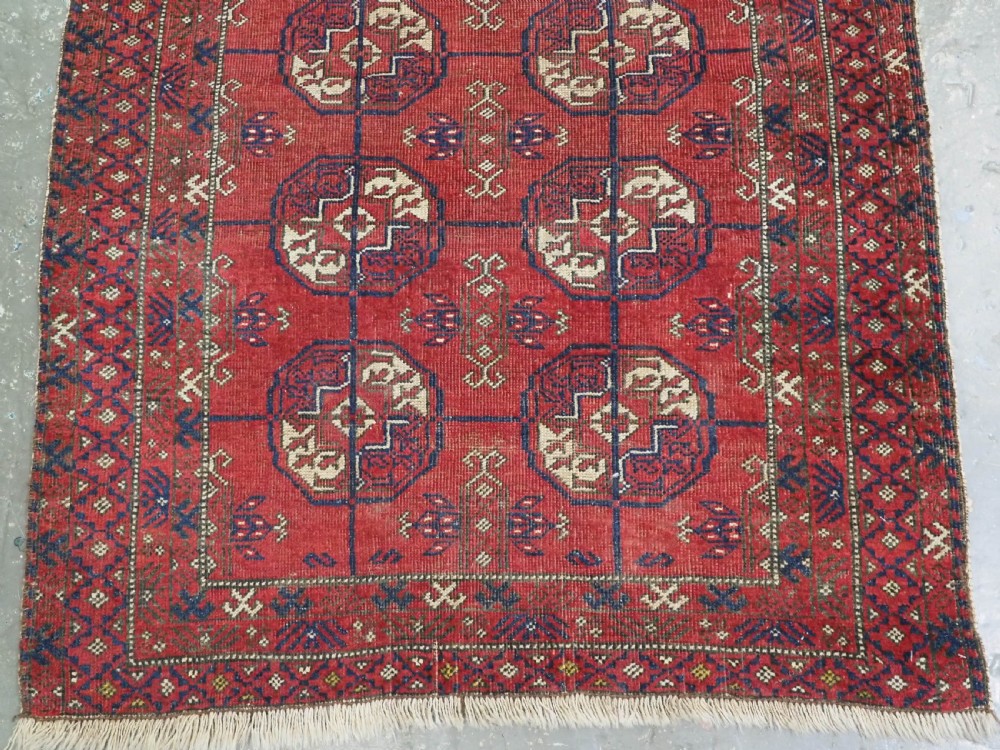 A hand-knotted antique Baluch prayer rug featuring a deep red ground, geometric octagonal medallions, an arched mihrab motif at the top, and multi-band patterned borders. View V
