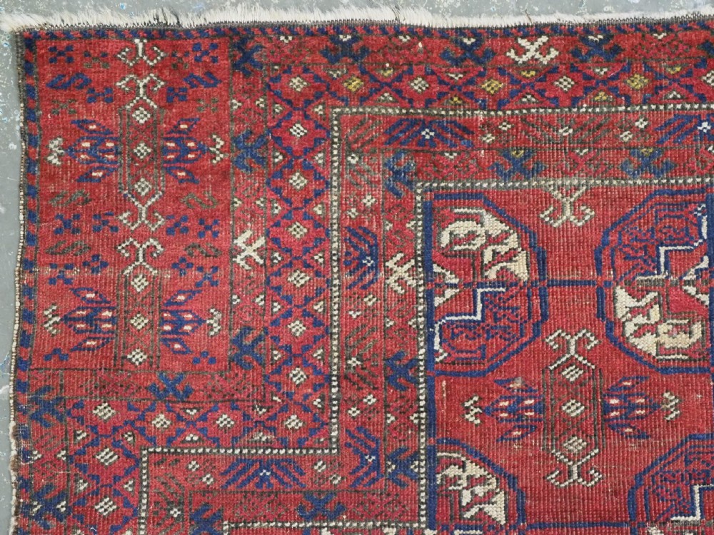 A hand-knotted antique Baluch prayer rug featuring a deep red ground, geometric octagonal medallions, an arched mihrab motif at the top, and multi-band patterned borders. View VI