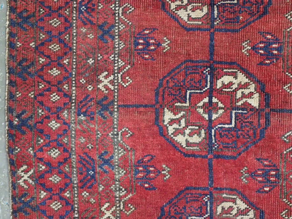 A hand-knotted antique Baluch prayer rug featuring a deep red ground, geometric octagonal medallions, an arched mihrab motif at the top, and multi-band patterned borders. View VII