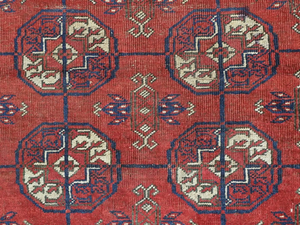 A hand-knotted antique Baluch prayer rug featuring a deep red ground, geometric octagonal medallions, an arched mihrab motif at the top, and multi-band patterned borders. View X