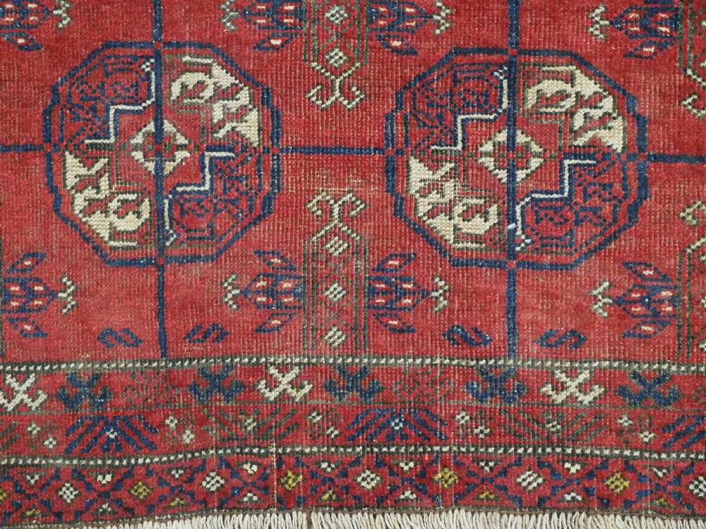 A hand-knotted antique Baluch prayer rug featuring a deep red ground, geometric octagonal medallions, an arched mihrab motif at the top, and multi-band patterned borders. View XI